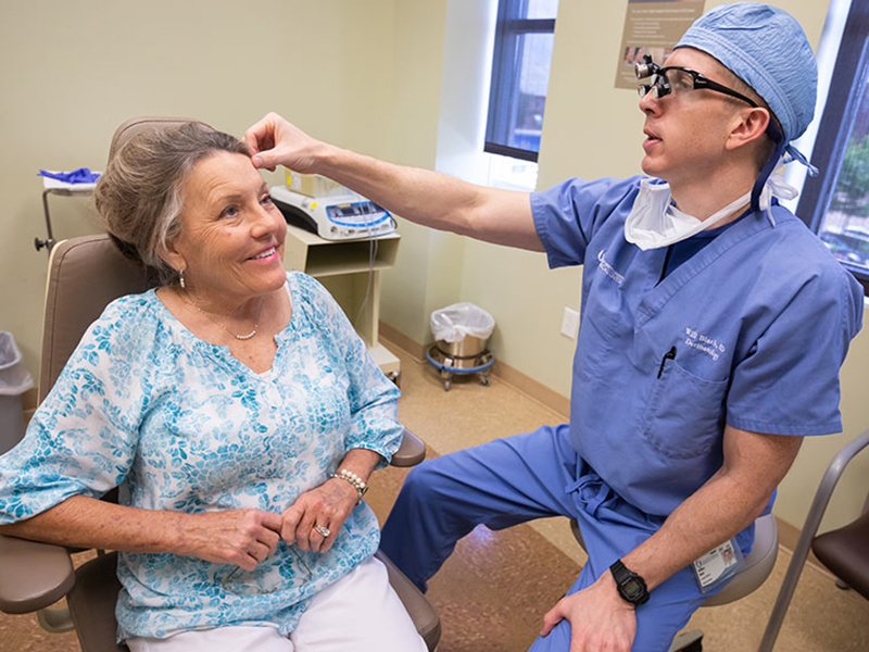 Dr. William Black, right, examines Linda Puckett's forehead. Black used Mohs surgery to remove a melanoma from the area.